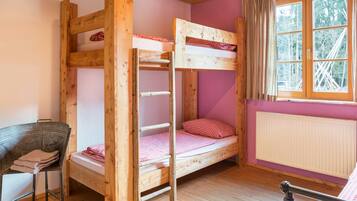 Une chambre avec un lit superposé, une fenêtre, une chaise et un radiateur.