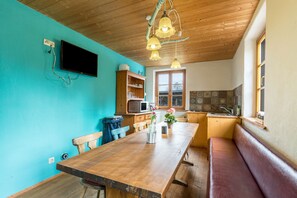 Eine Küche mit Holztisch, Bank und einem an der Wand befestigten Fernseher.