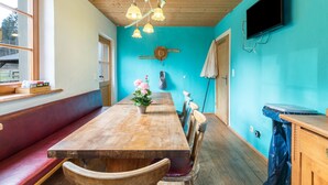 Ein Zimmer mit einem Holztisch, Bänken, einem Fernseher und einer blauen Wand.