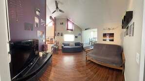 A living room with a flat-screen TV, a sofa, a coffee table, and a ceiling fan. - Pet friendly Bungalow. Close to Downtown and Mountains! (Lakewood)