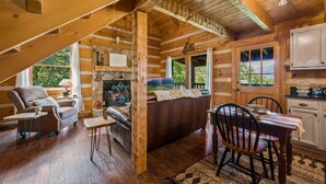 L’intérieur d’une cabane en rondins, avec une cheminée, des meubles en bois et un coin repas.