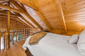 A wooden cabin bedroom with a bed, pillows, and a blanket. - Cabin with Amazing View near Nat’l Park (Sevierville)