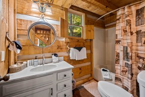 A wooden cabin bathroom with a sink, mirror, and window. - Cabin with Amazing View near Nat’l Park (Sevierville)
