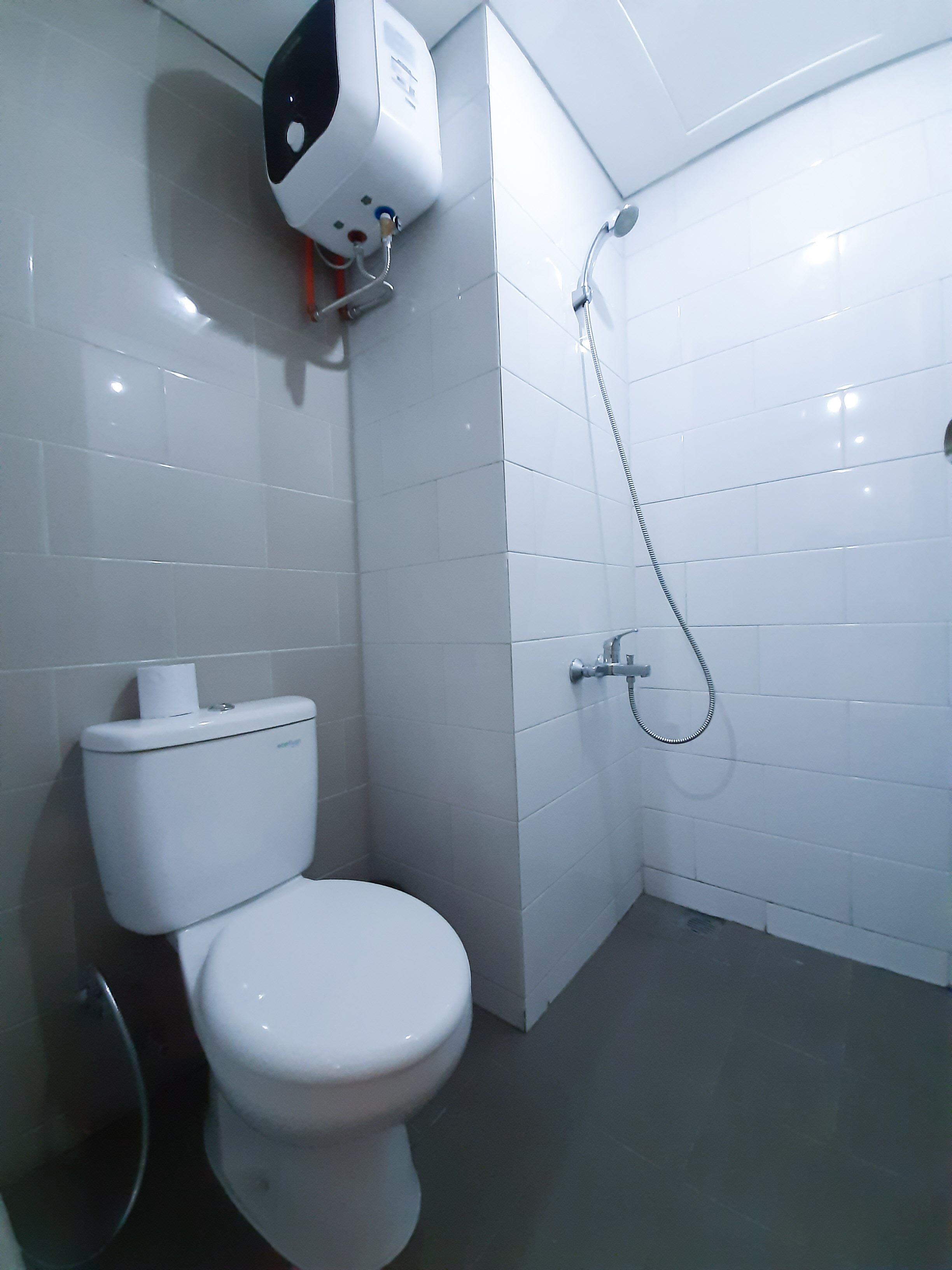 A modern bathroom with a toilet, a hand dryer, and a shower.