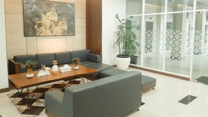 Een modern wachtgedeelte met een bank, een bijzettafeltje en decoratieve objecten.