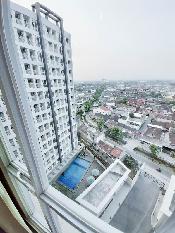 Un immeuble de grande hauteur doté de nombreux balcons et d’un espace piscine sur le toit.