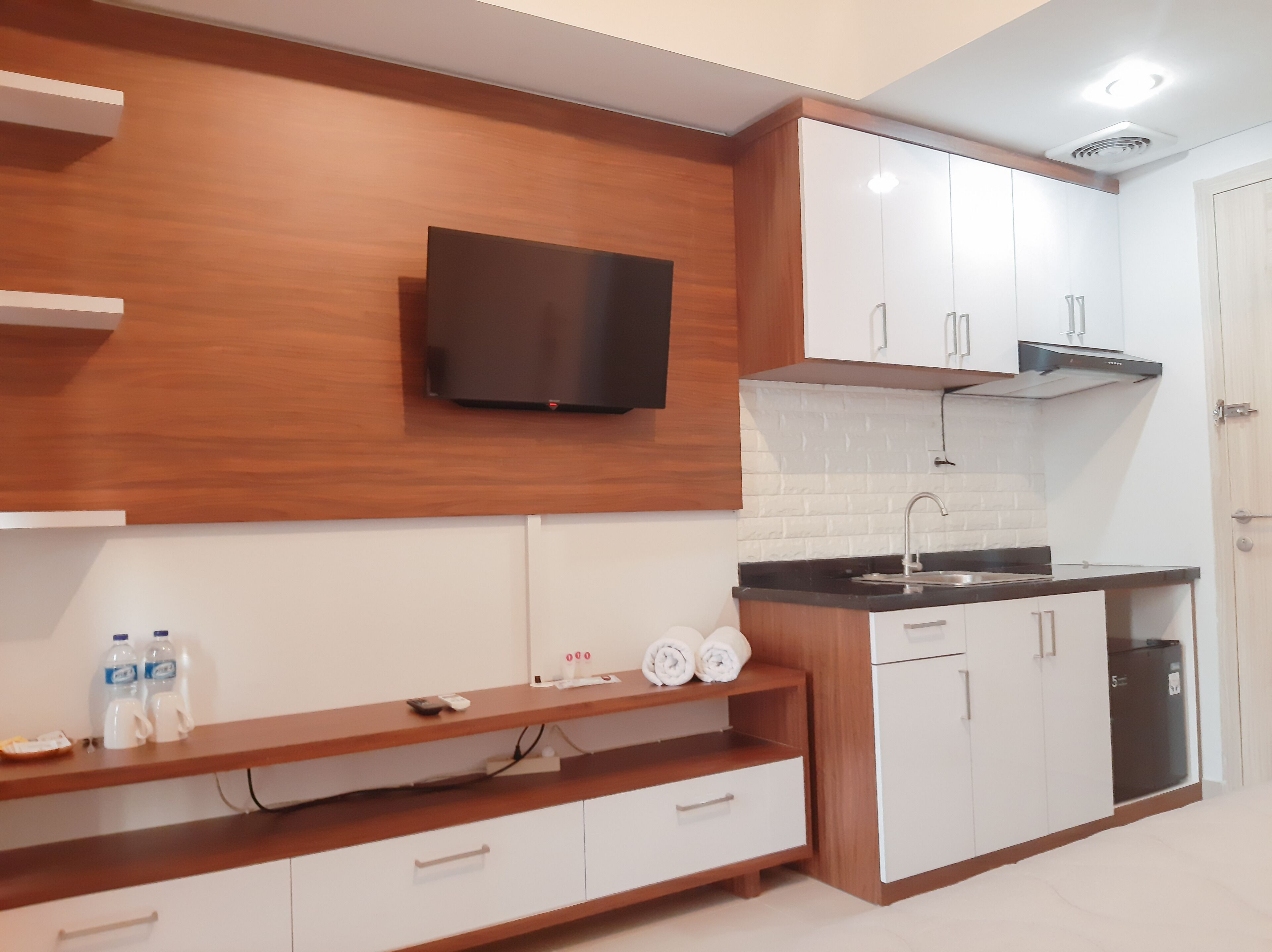 Une cuisine moderne avec des meubles en bois, un téléviseur encastré, un évier et un plan de travail.