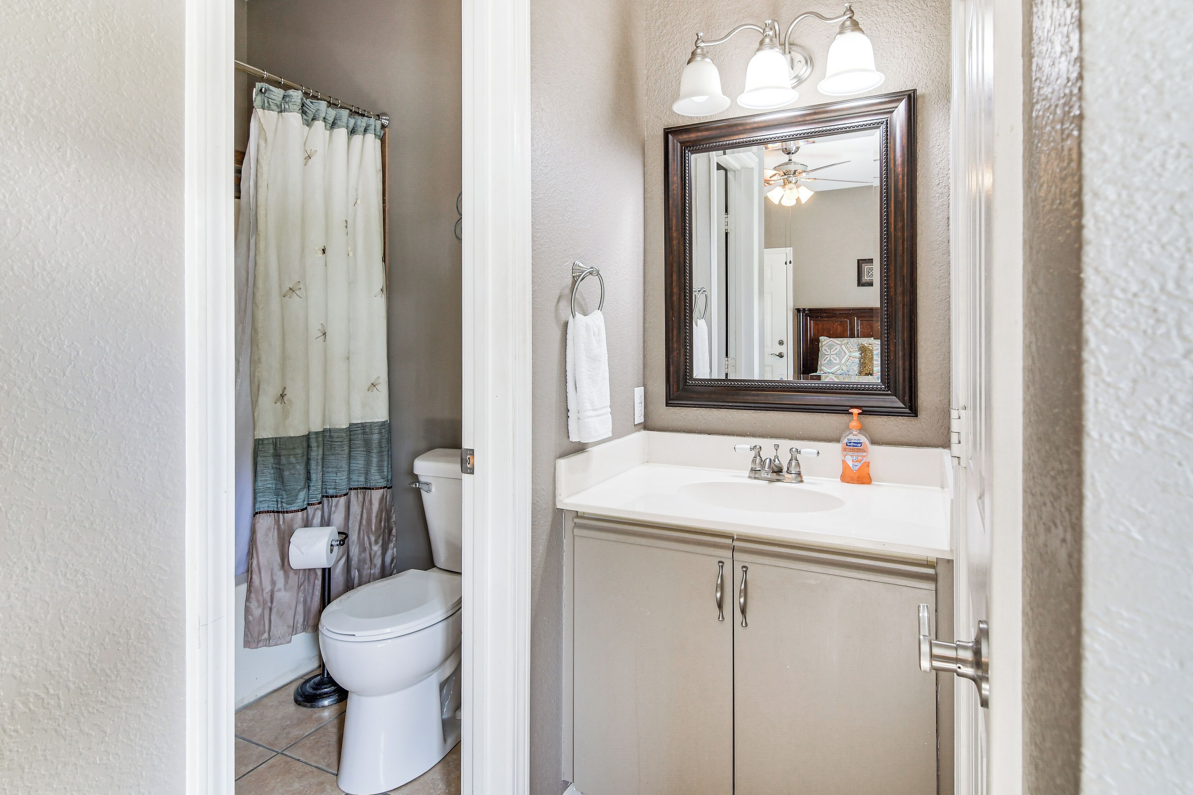 A bathroom with a toilet, a sink, and a mirror.
