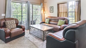 Een woonkamer met een bruine leren bank, een bijpassende fauteuil en een houten salontafel.