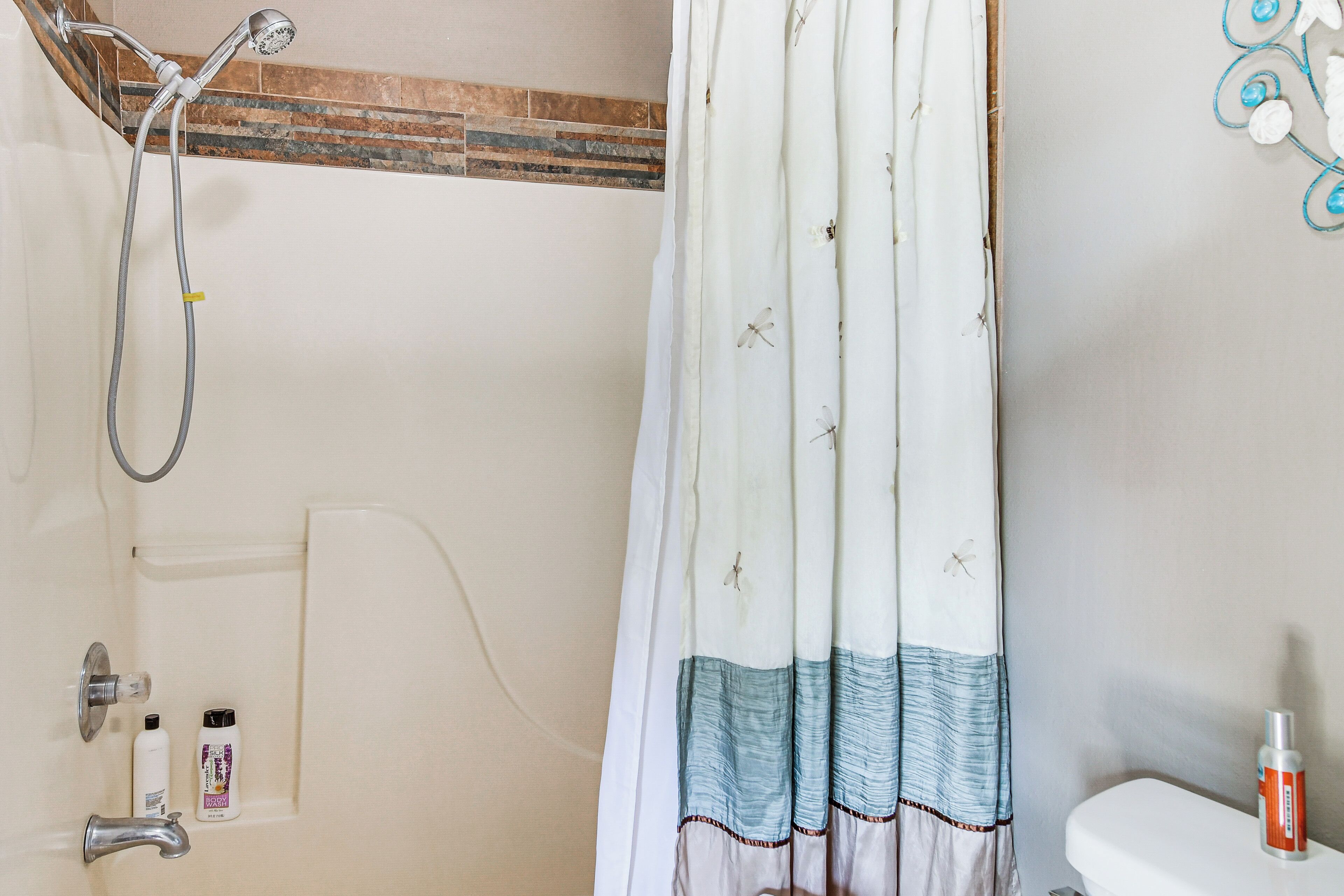 Ein Badezimmer mit Dusche, Toilette und einer Duschvorhangs mit Libellenmuster.