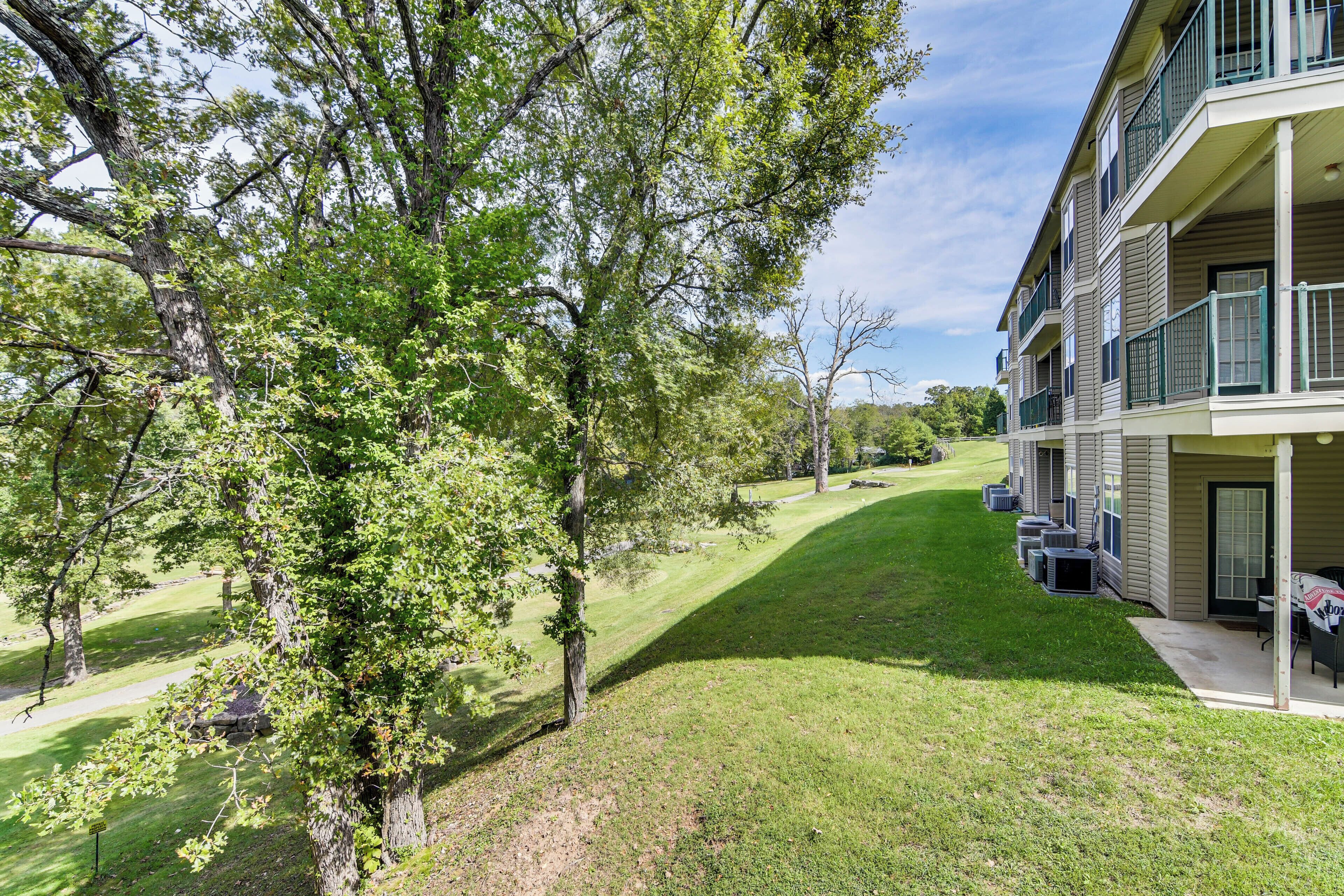 A multi-story building with balconies, a lawn, and trees.