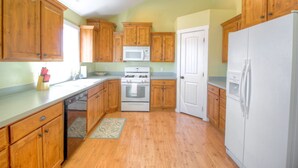 Una cocina con armarios de madera, microondas, estufa y refrigerador.