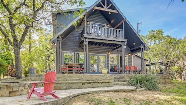 A wooden cabin with a balcony, stone steps, and outdoor seating. - Lakefront Chico Haven w/ Multi-Level Private Dock! (Chico)