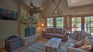A cozy living room with a stone fireplace, a mounted moose head, a sofa, and a coffee table. - Lakefront Chico Haven w/ Multi-Level Private Dock! (Chico)