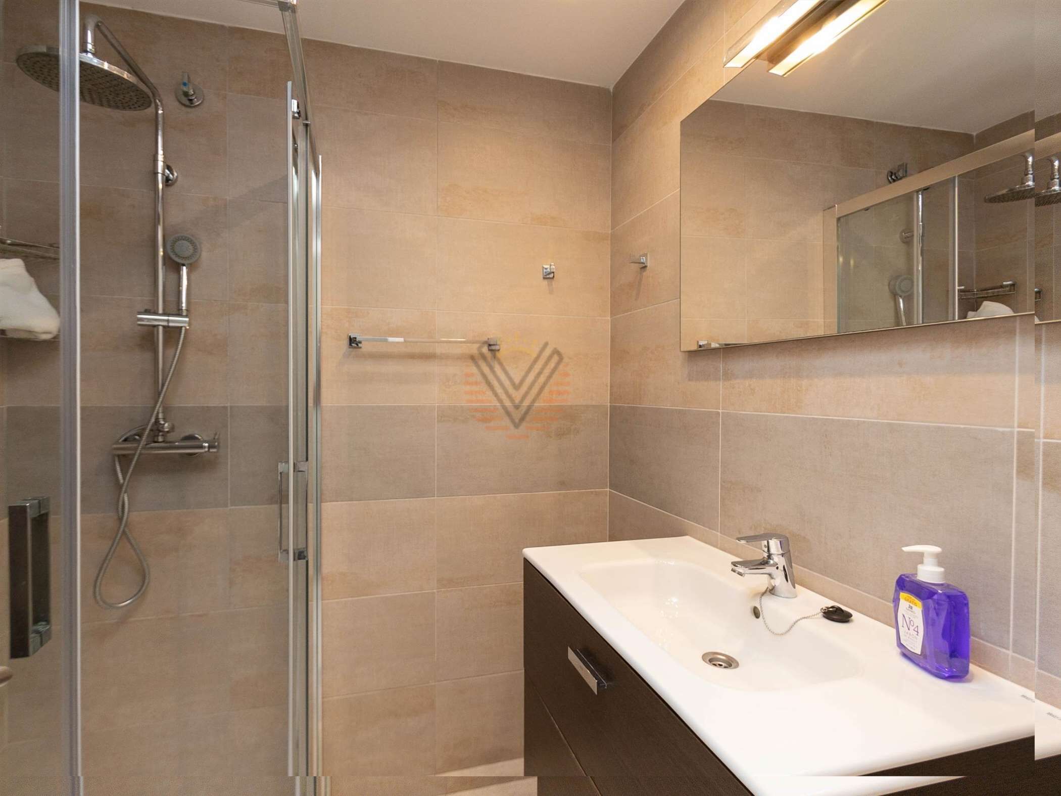 Un bany modern amb dutxa, un lavabo i un mirall.