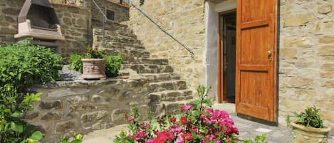 A stone building with a wooden door, a chimney, and potted plants.