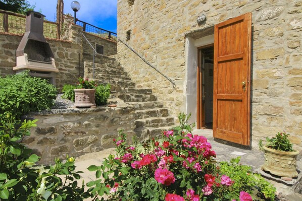 A stone building with a wooden door, a chimney, and potted plants.