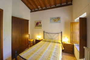 Una camera da letto con un letto, due comodini con lampade, un'armadio in legno e un quadro appeso al muro.