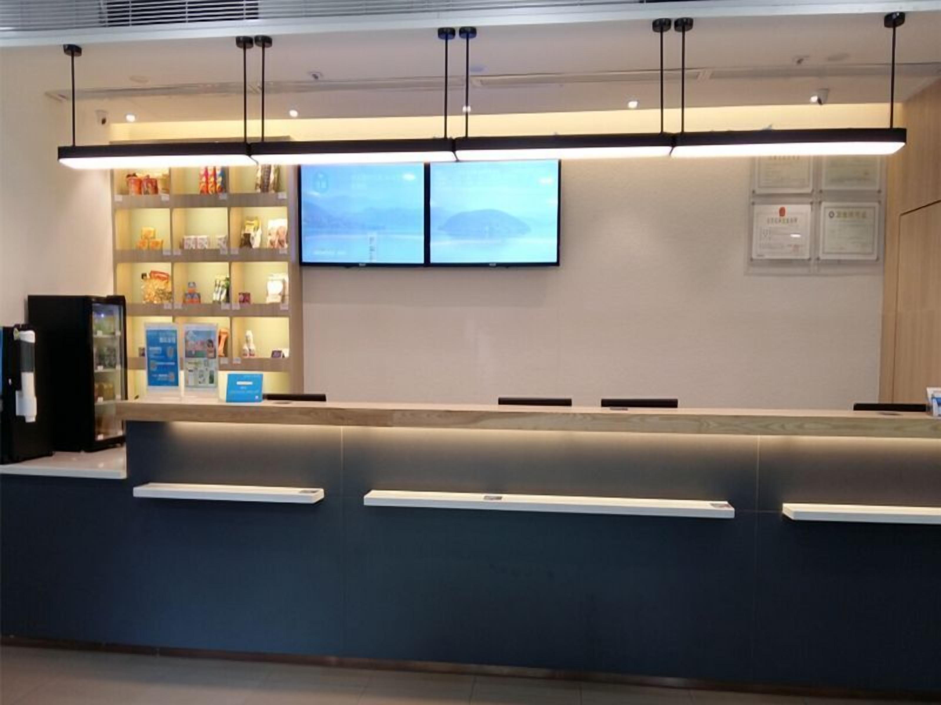 En receptionsdisk med en platt-TV, ett kylskåp och en utställning av produkter.