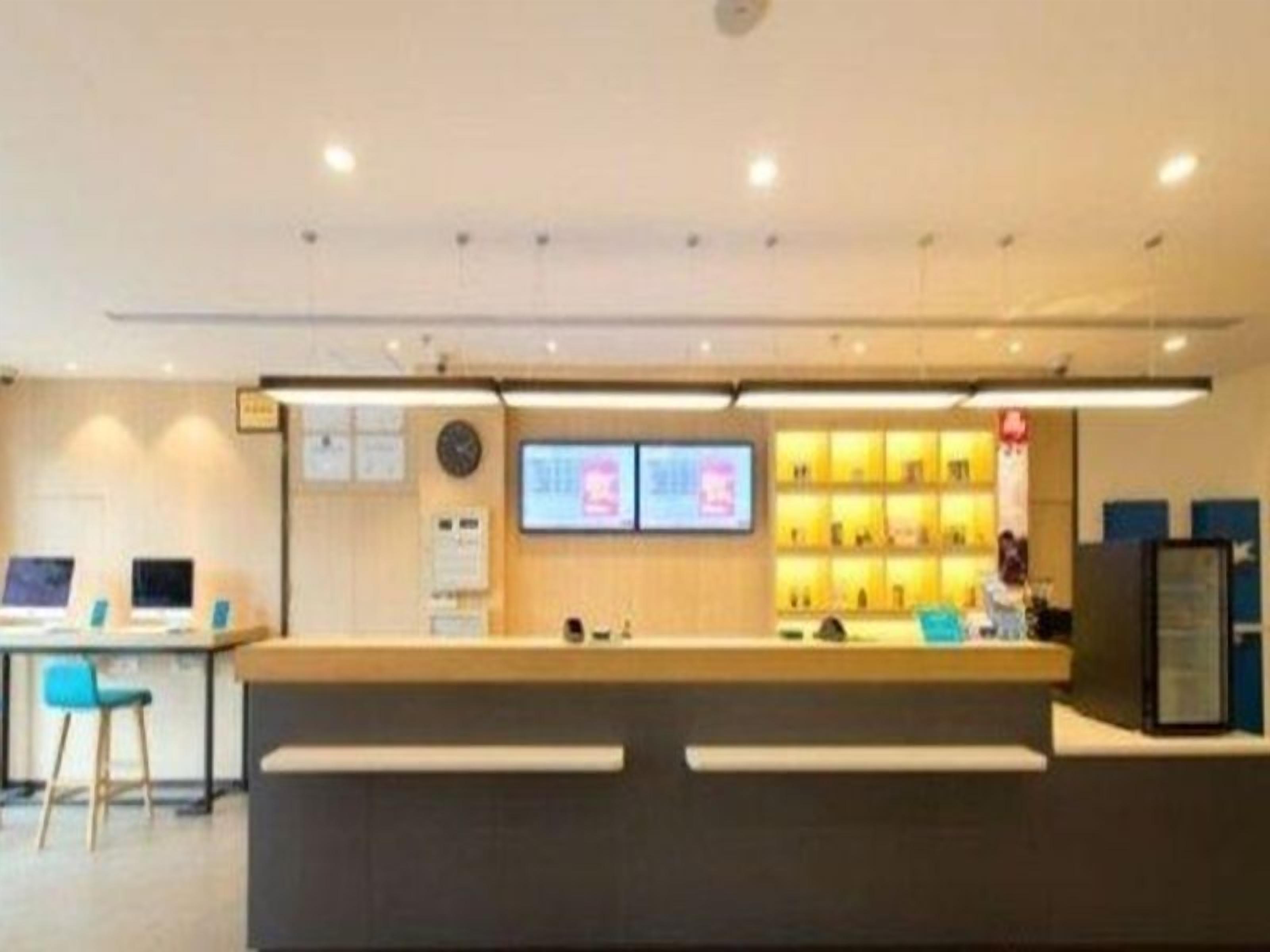 A reception desk with a computer, a clock, and a digital screen.
