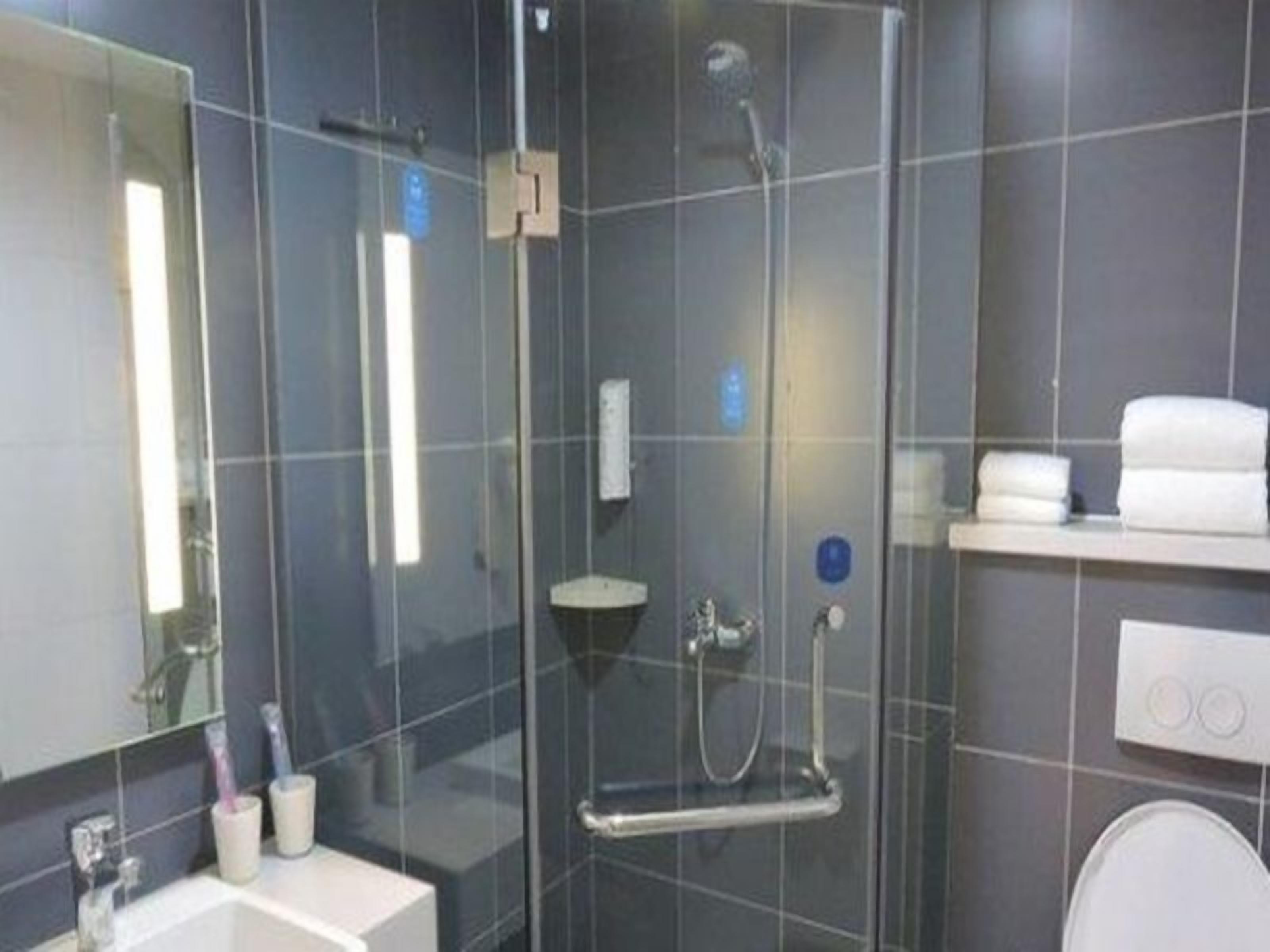 A modern bathroom with a glass-enclosed shower, a white sink, and a mirror.