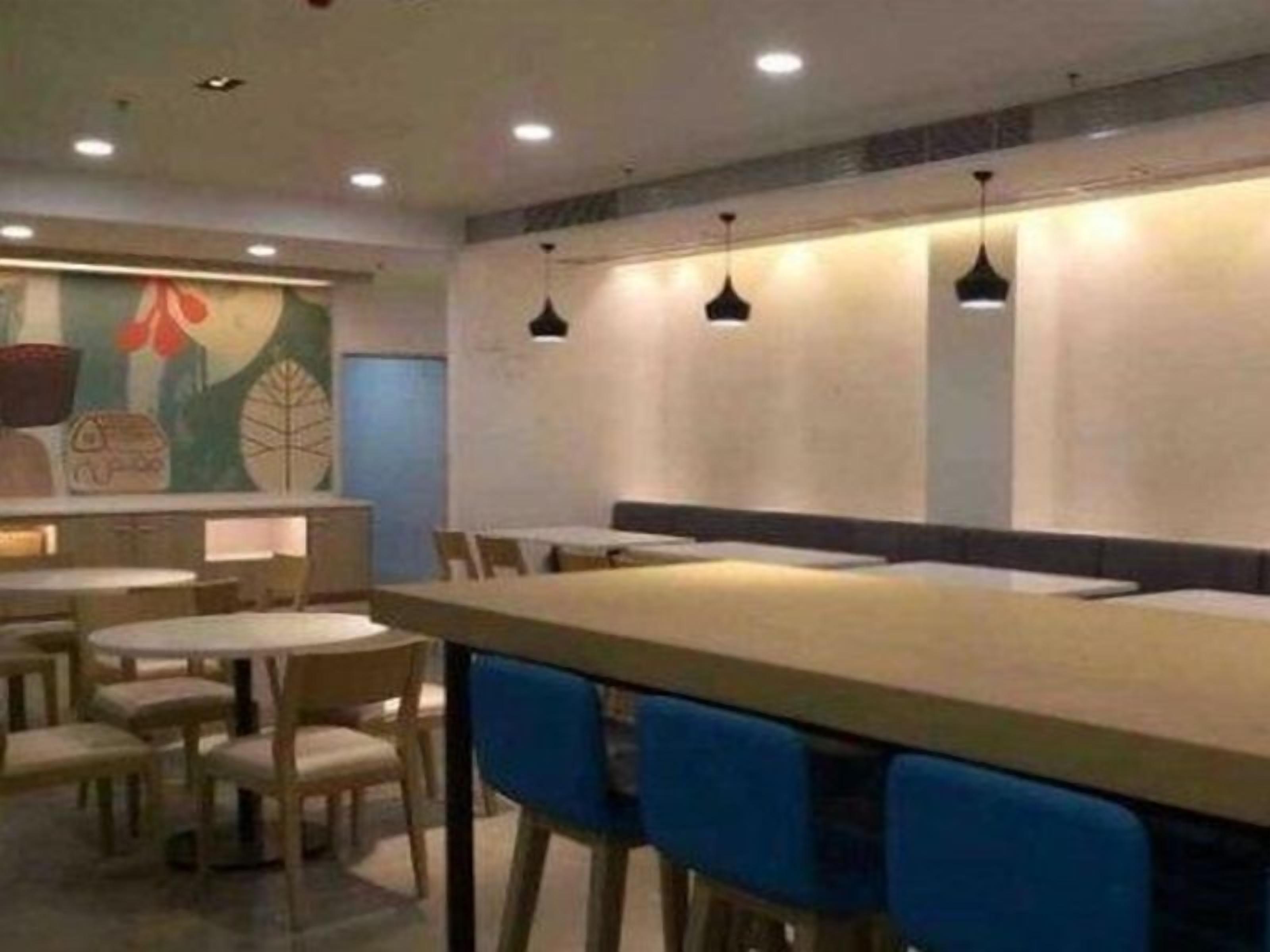 A restaurant interior with round tables, blue chairs, and pendant lighting.