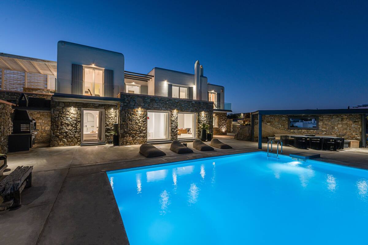 A modern house with a swimming pool, stone walls, and outdoor seating.