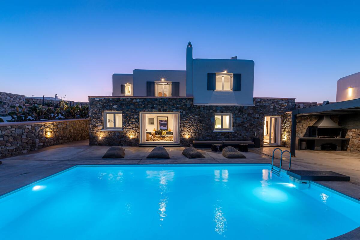 A modern house with a swimming pool, stone walls, and outdoor seating.