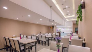 A restaurant with multiple tables and chairs, a counter area, and ceiling-mounted lights. - Lavande Hotel (Wuhan)