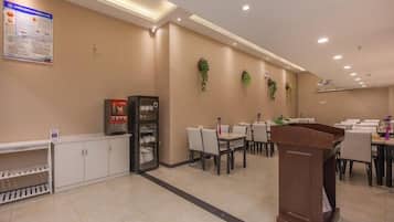 Um saguão de hotel com balcão de recepção, área de estar e um quadro de avisos.