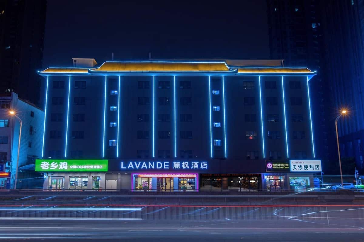 Un hotel con fachada moderna, varios pisos y señalización iluminada.