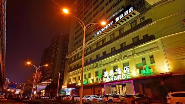 A hotel with a prominent sign, multiple floors, and a parking area. - Lavande Hotel (Wuhan)