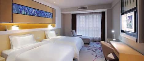 A hotel room with two beds, a desk, a chair, and a large window.