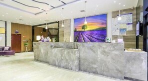 A hotel reception area with a marble reception desk, a painting of a sunset over a field, and a wooden wall. - Lavande Hotel (Wuhan)