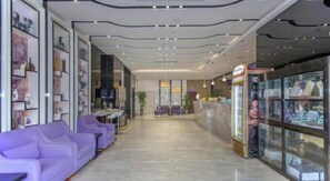 A reception area with a reception desk, purple seating, and a display case with items. - Lavande Hotel (Wuhan)