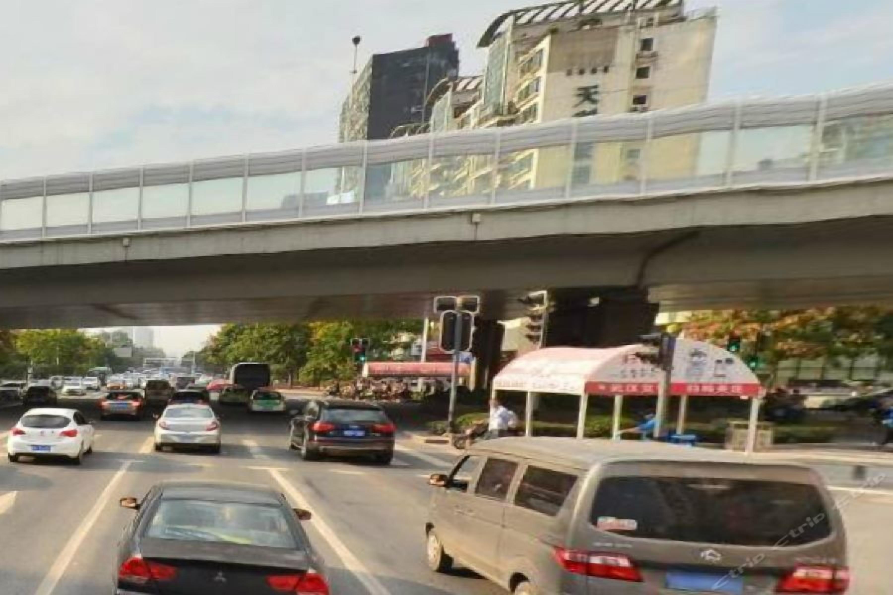 A busy urban street with a pedestrian overpass, vehicles, and commercial signage.