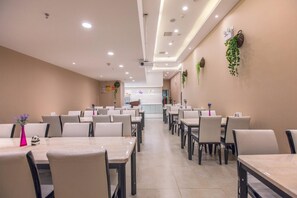 A spacious dining area with multiple tables and chairs, a clean and modern interior design, and a visible counter in the background. - Lavande Hotel (Wuhan)
