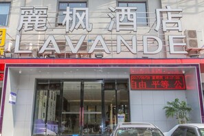 A hotel with a large sign reading 'LAVANDE' and a digital display showing the date and time. - Lavande Hotel (Wuhan)