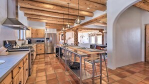 A modern kitchen with wooden beams, stainless steel appliances, and a long island with stools.