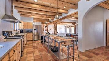A modern kitchen with wooden beams, stainless steel appliances, and a long island with stools.