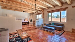 A spacious living area with a high wooden ceiling, a fireplace, a sofa, and a coffee table.