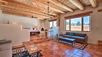 A spacious living area with a high wooden ceiling, a fireplace, a sofa, and a coffee table.