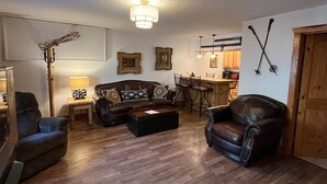 Ein Wohnzimmer mit braunem Ledersofa, einem Holztisch und einer Essecke mit Bar.