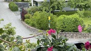 A modern building with a courtyard, surrounded by greenery and a church in the background. - Haus Lukas (Hopfgarten im Brixental)