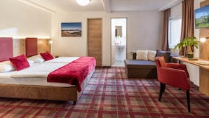 A hotel room with a bed, a desk, a chair, a sofa, a potted plant, and a painting on the wall. - Haus Lukas (Hopfgarten im Brixental)
