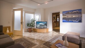 A modern living room with a flat-screen TV, a potted plant, and a large window. - Haus Lukas (Hopfgarten im Brixental)