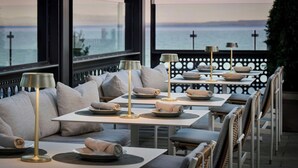 A restaurant with tables set for dining, large windows with a view of the sea, and a modern interior design. - The Pearle Hotel & Spa, Autograph Collection (Burlington)