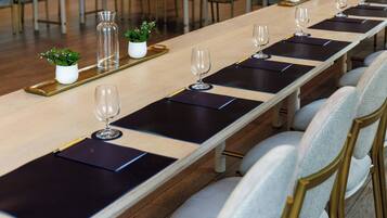 A long conference table with black placemats, clear glass vases, and small potted plants.
