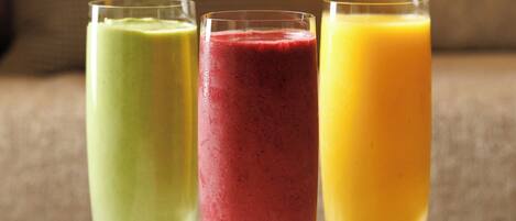 Three glasses of smoothies on a marble surface.