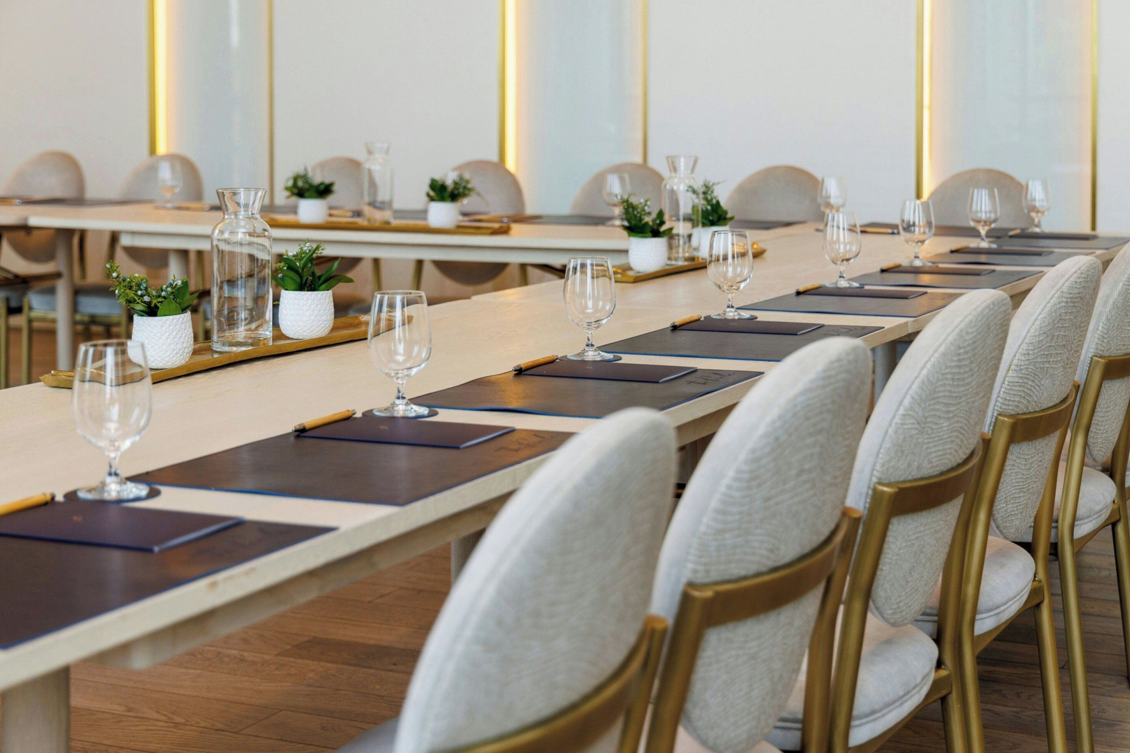 A conference room with long tables, chairs, and glassware.
